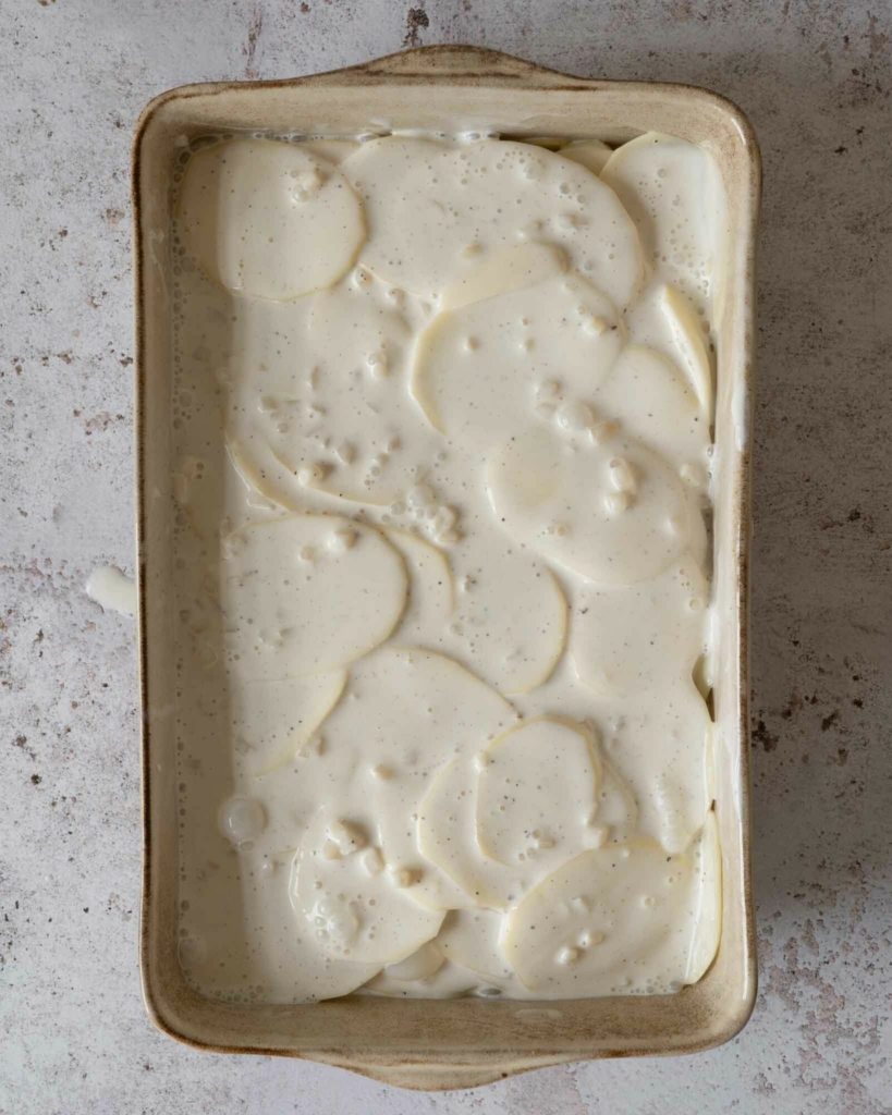 Vegan potatoes dauphinoise in a baking dish about to go in the oven