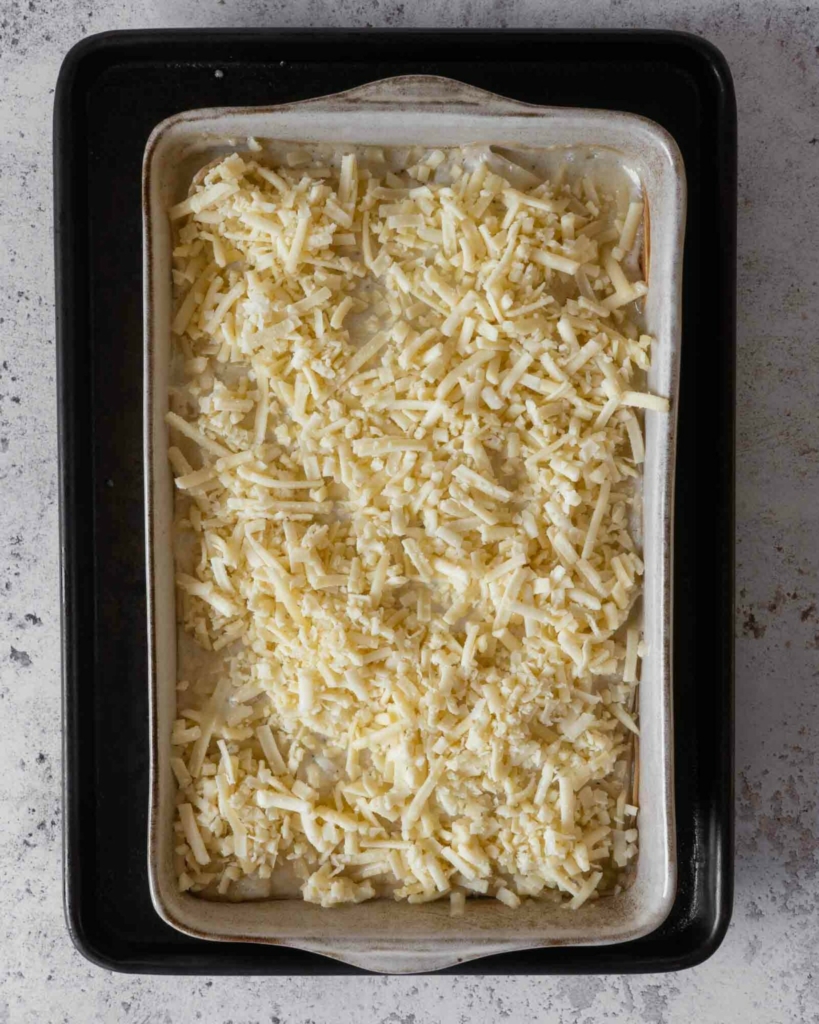 Cheesy potatoes au gratin in a baking dish about to go in the oven