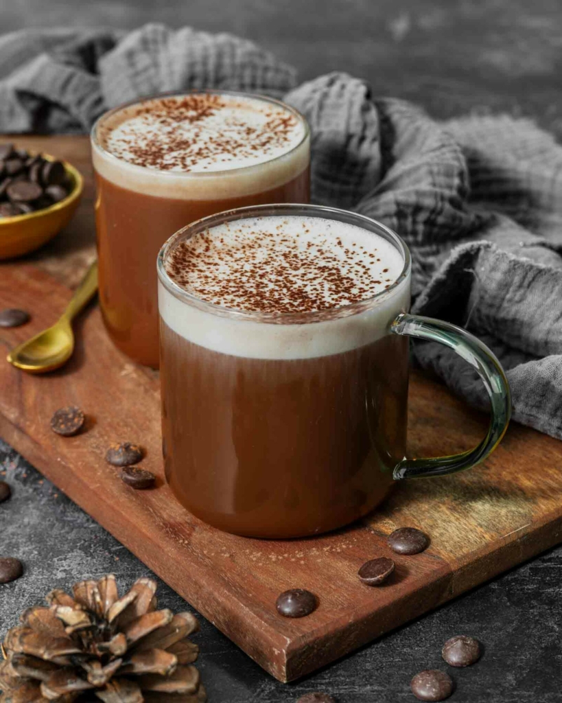 Vegan hot chocolate in two glass mugs, topped with frothy oat milk