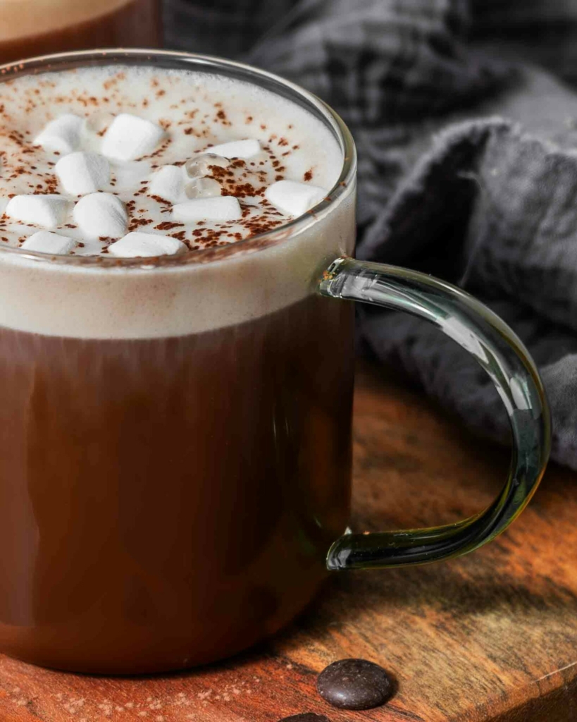 A mug of hot chocolate topped with frothy oat milk and vegan marshmallows