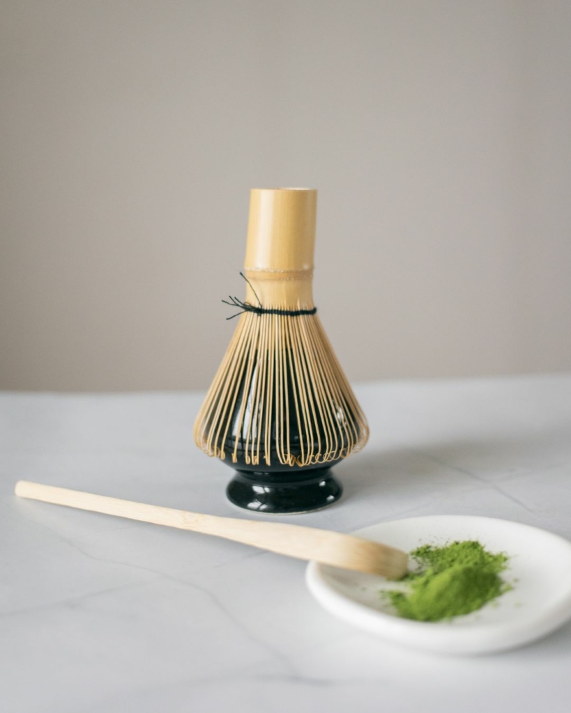 A bamboo matcha whisk on a stand