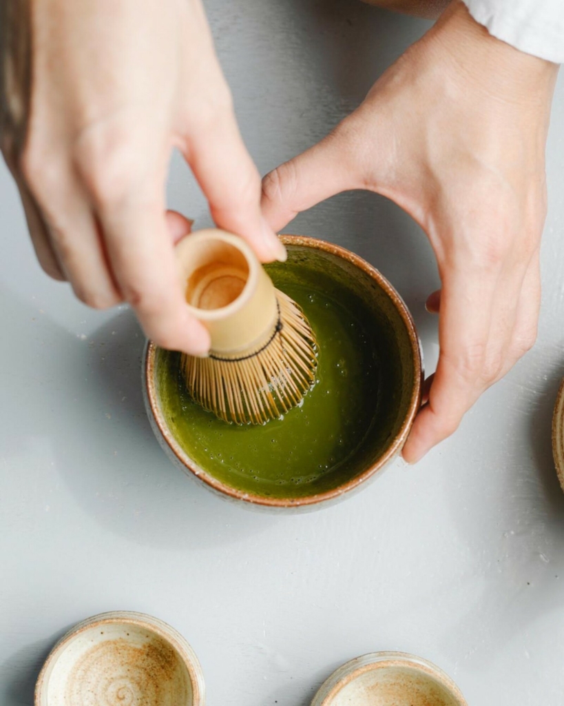 How to use matcha whisk; hands whisking a bowl of matcha