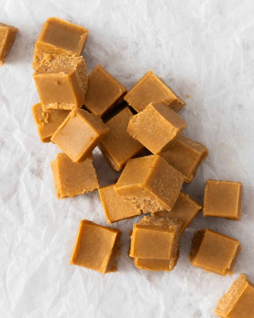 Cubes of 3 ingredient peanut butter fudge no milk spread out on a table top