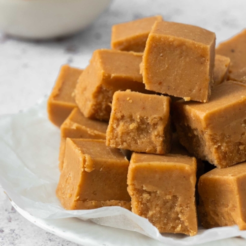 A plate stacked high with 3 ingredient peanut butter fudge no milk