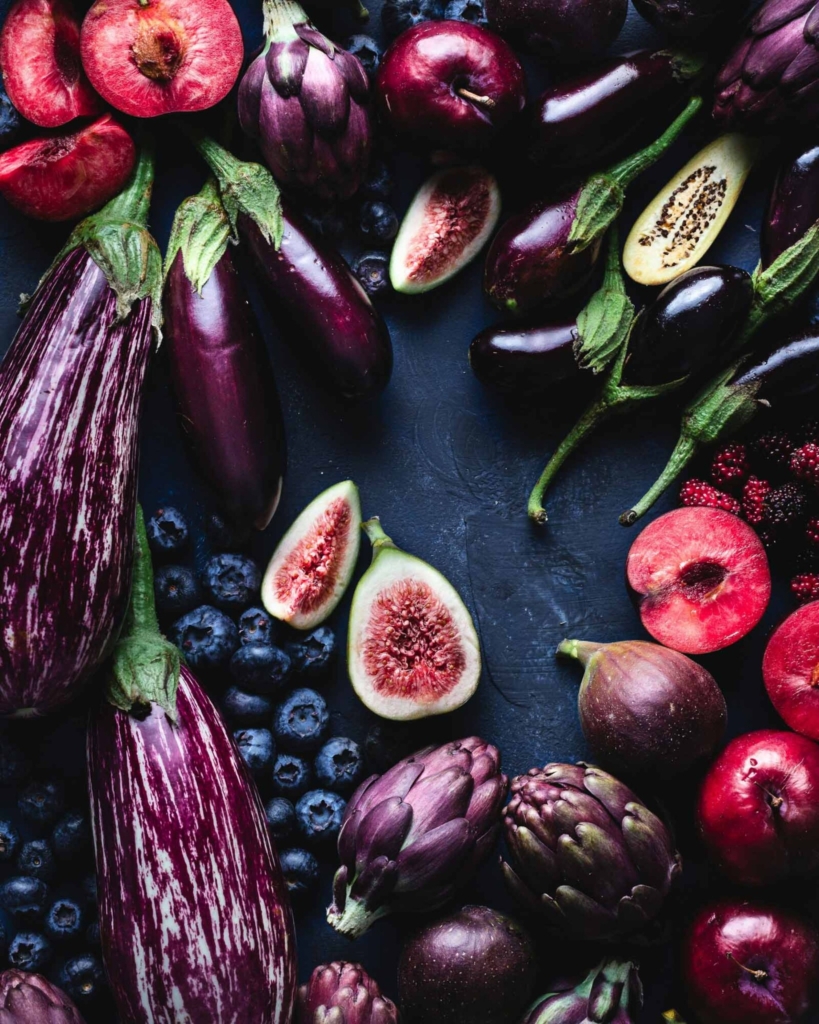 A range of purple and pink fruits and vegetables on a dark background