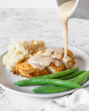 Pouring a white gravy recipe without milk over a vegan chicken kiev
