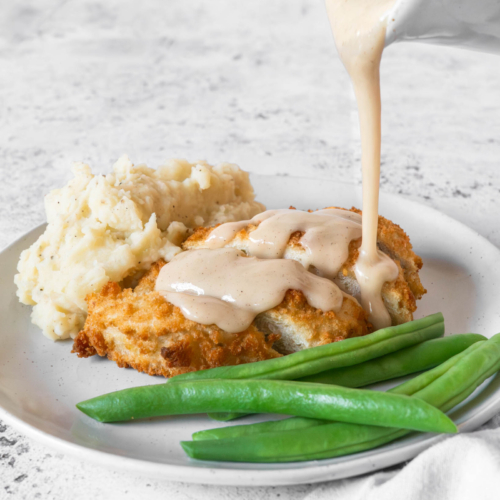 Pouring a white gravy recipe without milk over a vegan chicken kiev