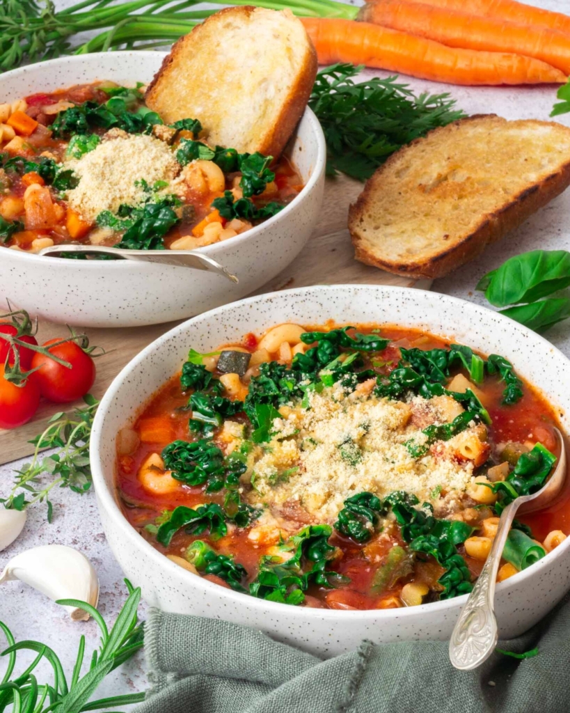 Two bowls filled with a zuppa del giorno recipe - vegetable and bean soup, with a side of toasted sourdough bread