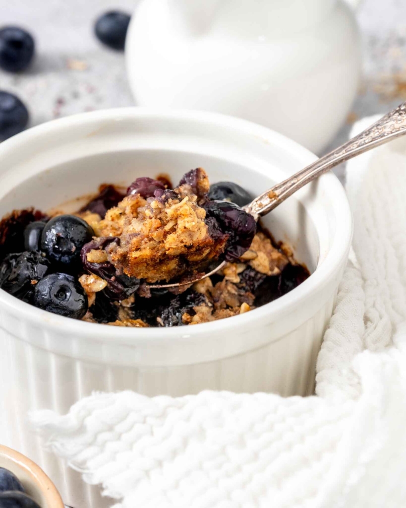 A spoonful of vegan baked oatmeal being taken from a ramekin