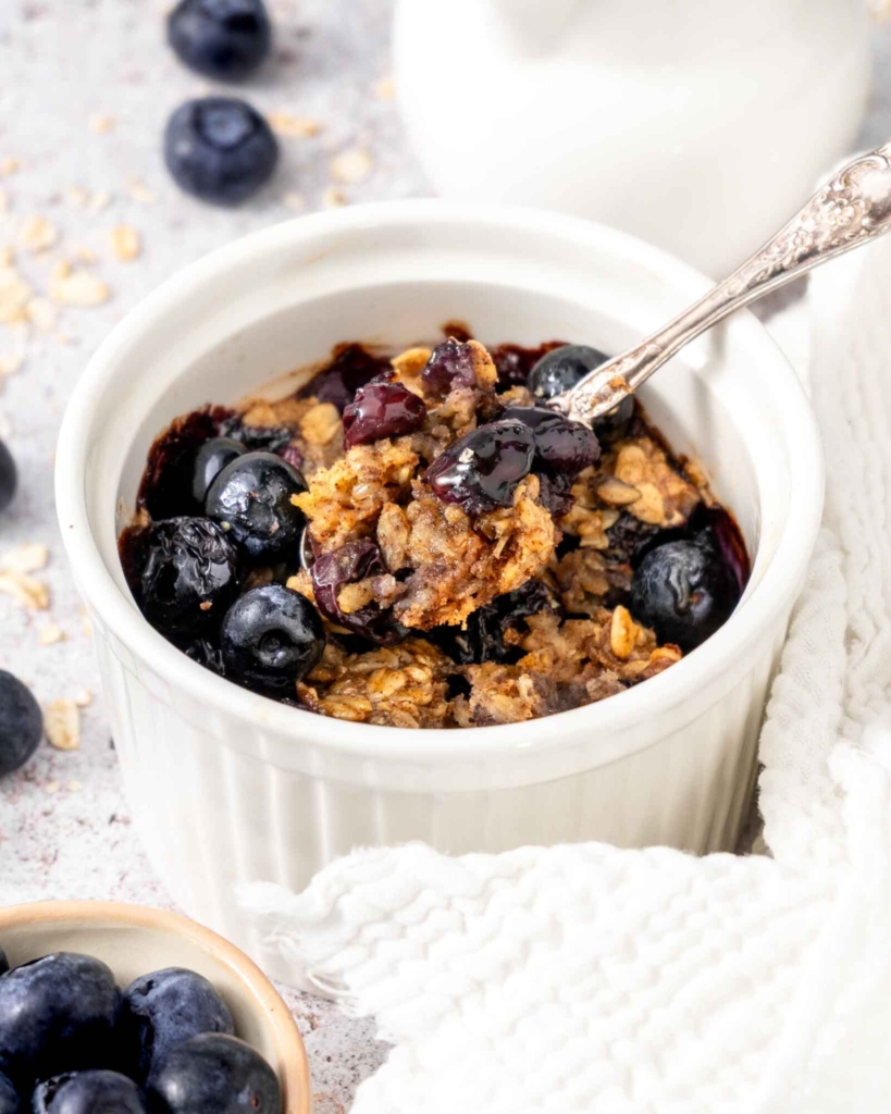A spoonful of vegan baked oatmeal being taken from a ramekin