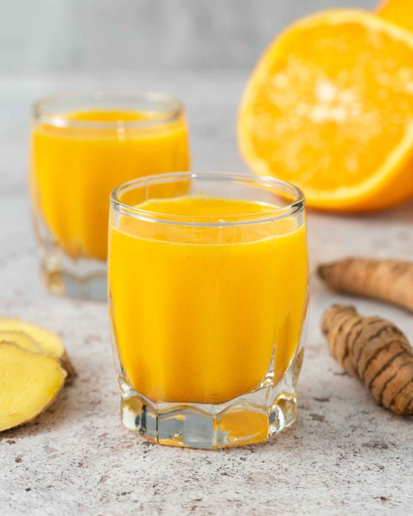 A fresh orange ginger turmeric shot in a glass