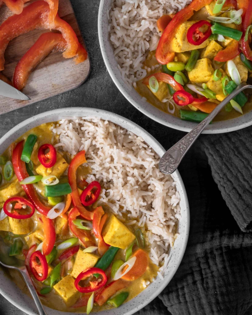 Two bowls of colourful vegan Chinese curry with rice