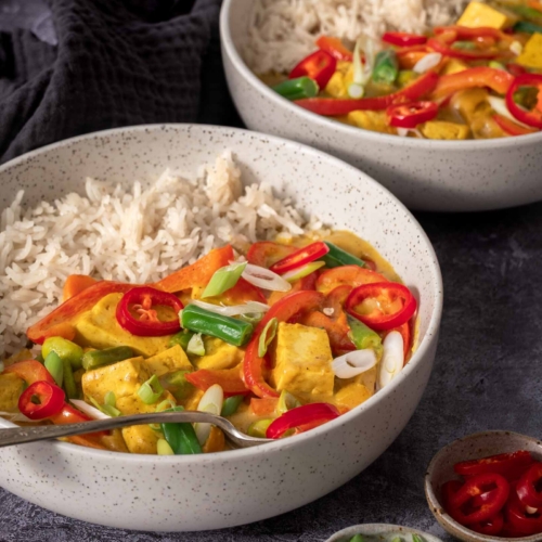 A side on photograph of two bowls of colourful vegan Chinese Curry