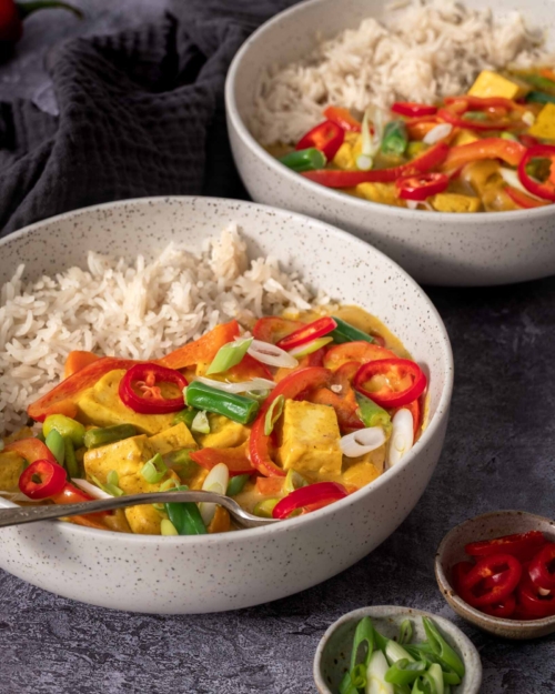 A side on photograph of two bowls of colourful vegan Chinese Curry
