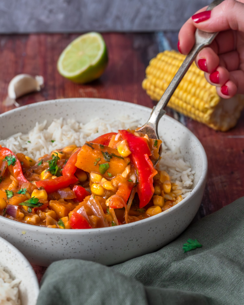 A colourful sweet corn, squash and red pepper curry in a bowl